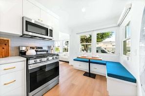 A modern kitchen with white cabinetry, a built-in oven, a stove, and a microwave. - The Tourmaline Beach House - Walk to Surf & Sand (San Diego)