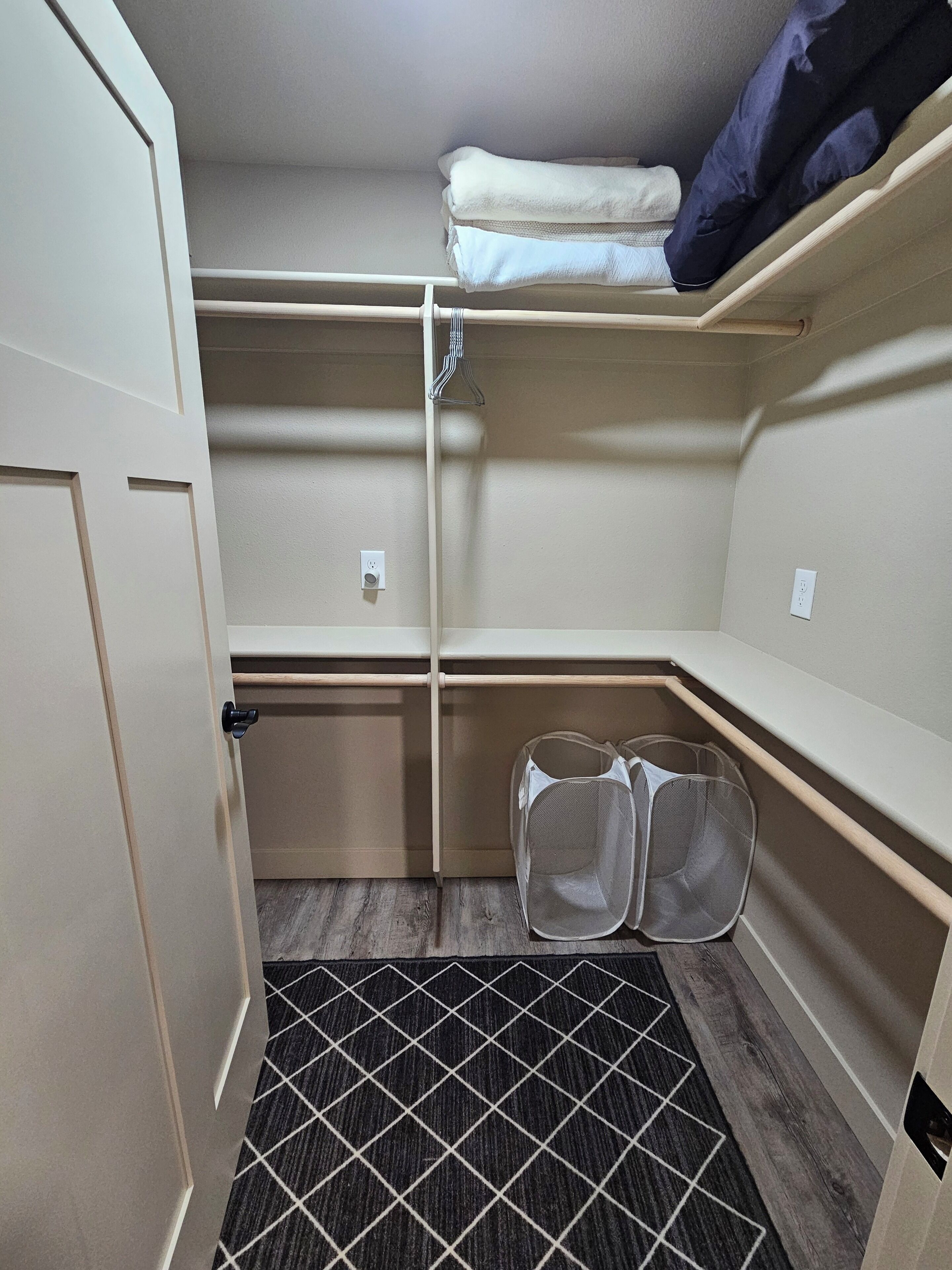 A compact storage closet with shelves, a hanging rack, and a mesh laundry basket.