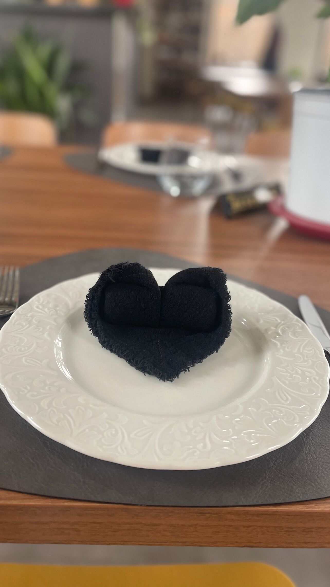 A plate with a heart-shaped food item on a white plate with a grey napkin underneath.