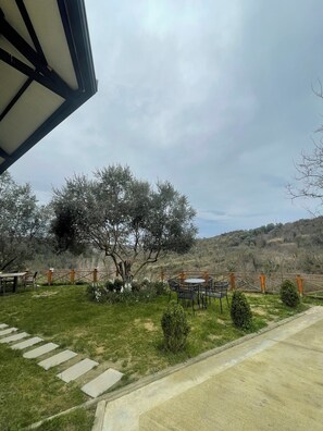 An outdoor seating area with tables and chairs, a wooden fence, and a tree.