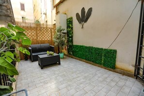 A patio with a sofa and coffee table, a wall-mounted decorative element, and a green wall accent. - Loft con Archi Romani | Cuore di Trastevere (Rome)