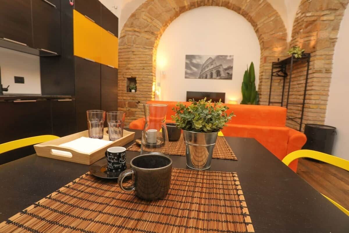 Ein Essbereich mit einem Tisch für zwei Personen, einem Blumentopf und einem gerahmten Bild an der Wand.