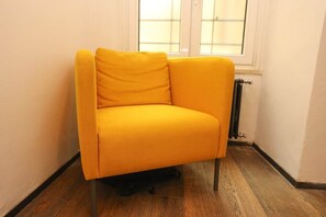 A yellow armchair in a corner with a radiator and wooden flooring. - Loft con Archi Romani | Cuore di Trastevere (Rome)
