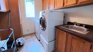 A compact kitchen with wooden cabinets, a built-in washing machine, a refrigerator, and a sink.