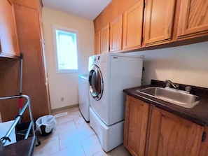 A compact kitchen with wooden cabinets, a built-in washing machine, a refrigerator, and a sink.