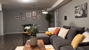 A living room with a gray sofa, a wooden coffee table, and a patterned rug.