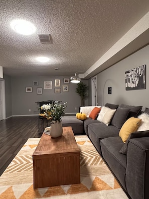 A living room with a gray sofa, a wooden coffee table, and a patterned rug.