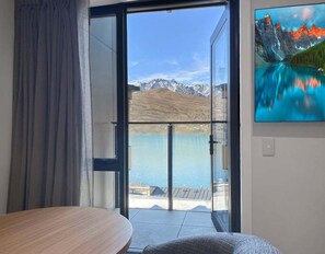 Ein Zimmer mit einer großen Glasdoor, die auf einen Balkon mit Bergblick und Seeblick führt.