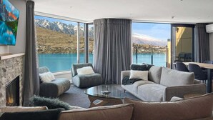 Una sala de estar moderna con chimenea, asientos cómodos y un amplio ventanal con vistas a la montaña.
