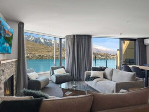 Ein modernes Wohnzimmer mit Kamin, bequemen Sitzmöglichkeiten und einem großen Fenster mit Blick auf die Berge.