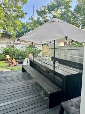 Eine Holzterrasse mit Bänken und einem Sonnenschirm.
