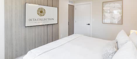 Een slaapkamer met een bed, een lijst aan de muur en een deur.