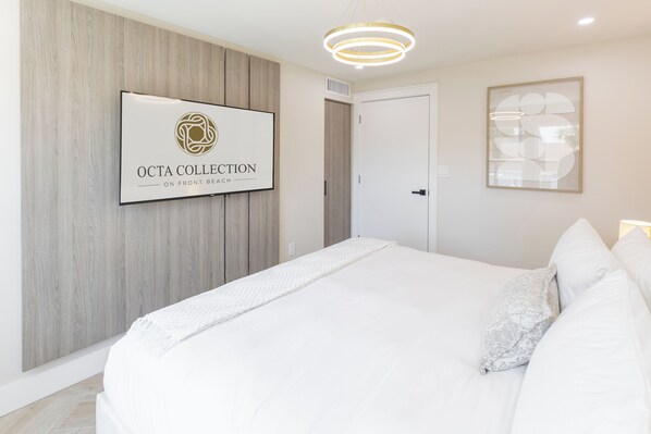 A bedroom with a bed, a framed sign on the wall, and a door.