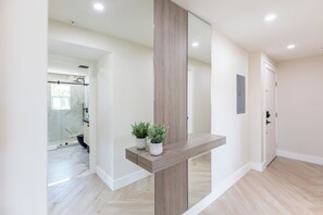 A hallway with a wooden accent wall, a potted plant, and a door. - Octa Collection on Front Beach (Panama City Beach)
