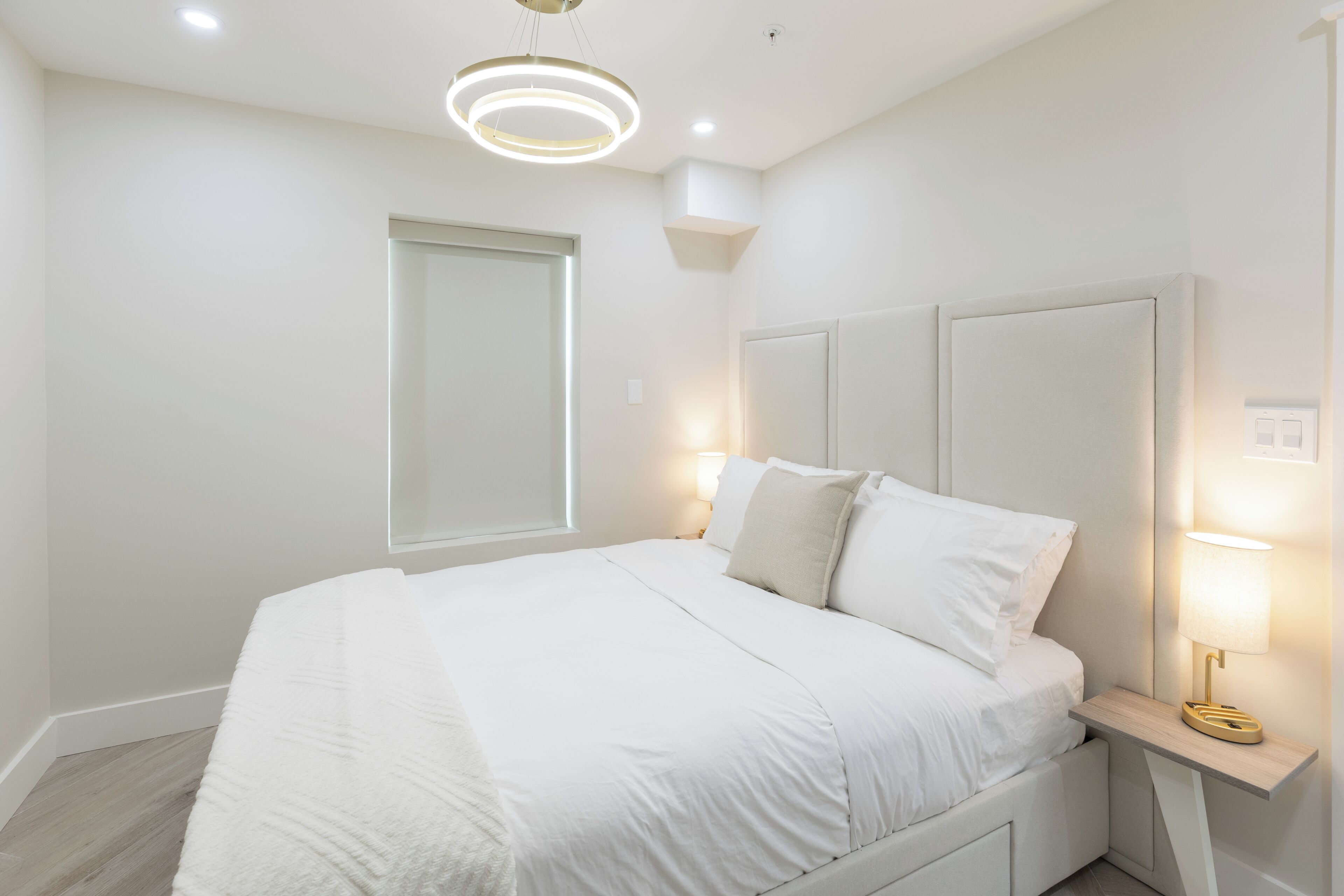Une chambre à coucher moderne avec un grand lit, des lampes de chevet et un luminaire circulaire au plafond.