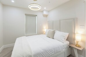 A modern bedroom with a large bed, bedside lamps, and a circular ceiling light. - Octa Collection on Front Beach (Panama City Beach)