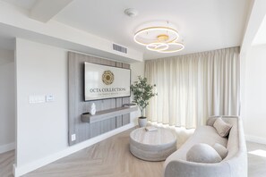 Una sala de estar moderna con un televisor montado, una mesa de centro redonda, un sofá y una planta en maceta.
