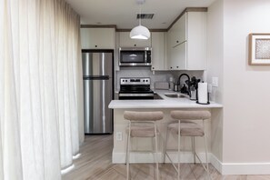 A modern kitchen with a built-in island, stainless steel appliances, and bar stools.