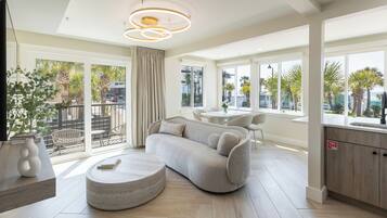 A modern living room with a sofa, a coffee table, and a dining area with chairs.