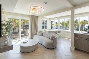A modern living room with a sofa, a coffee table, and a dining area with chairs.