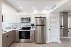 A modern kitchen with stainless steel appliances, wooden cabinets, and a herringbone-patterned floor. - Octa Collection on Front Beach (Panama City Beach)