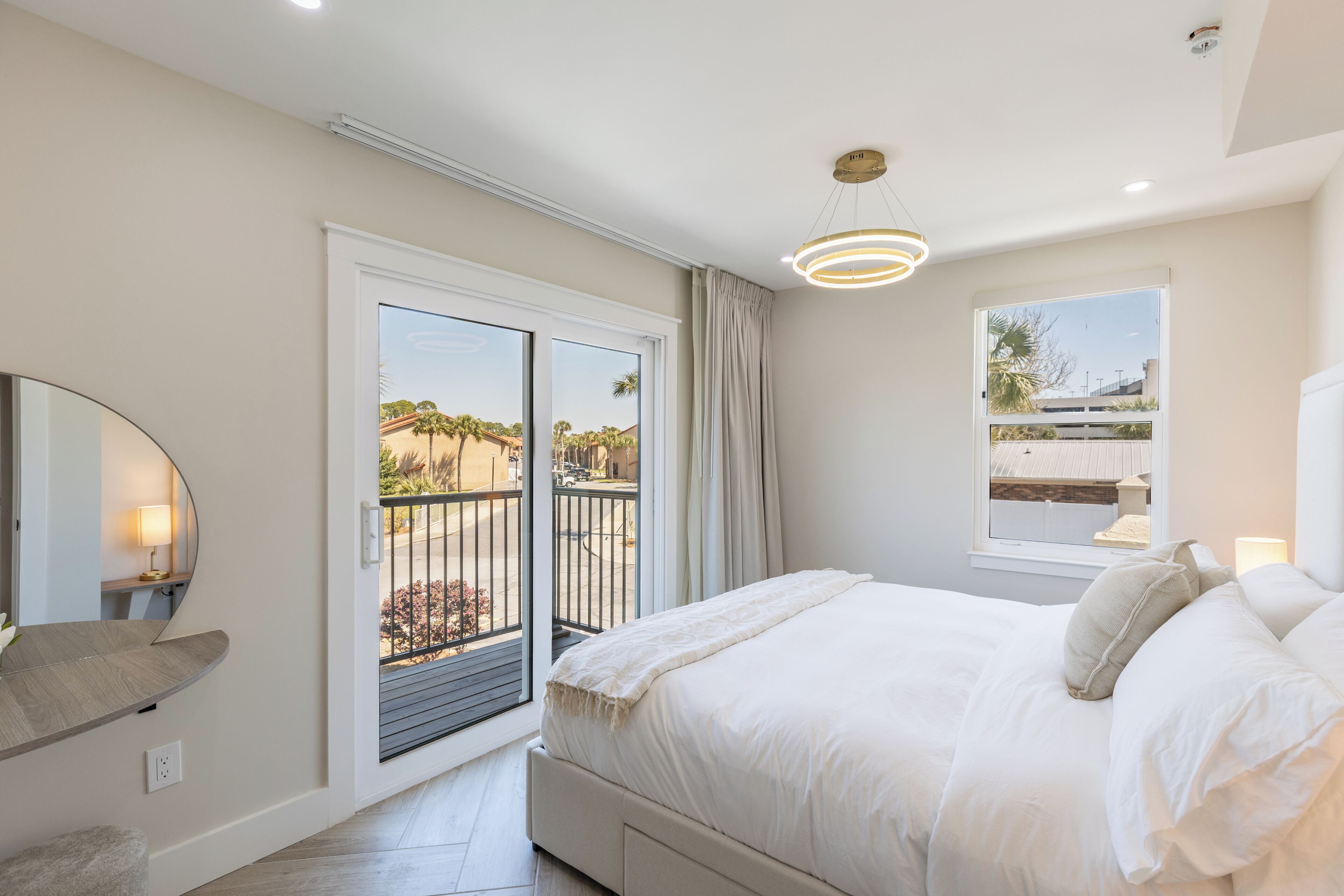 Une chambre à coucher avec un lit, une fenêtre donnant sur un beau paysage, un luminaire au plafond et une porte qui mène à un balcon.