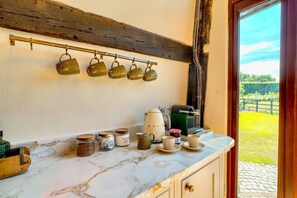 Une cuisine dotée d’un plan de travail en marbre, de tasses suspendues et de divers ustensiles de cuisine.
