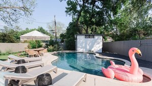 A swimming pool with lounge chairs and a flamingo float. - South Congress Oasis | Pool, Hot Tub & Sunroom (Austin)