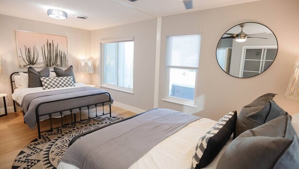 A bedroom with a bed, bedside tables, a ceiling fan, and a large window. - South Congress Oasis | Pool, Hot Tub & Sunroom (Austin)