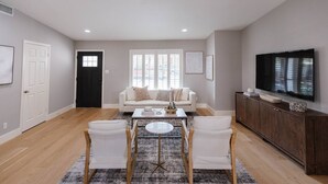 A spacious living room with a sofa, coffee table, and chairs. - South Congress Oasis | Pool, Hot Tub & Sunroom (Austin)
