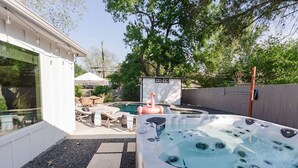 A backyard with a hot tub, a wooden deck, outdoor furniture, and a small shed. - South Congress Oasis | Pool, Hot Tub & Sunroom (Austin)