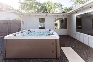 A hot tub in a backyard with a wooden deck and a window. - South Congress Oasis | Pool, Hot Tub & Sunroom (Austin)