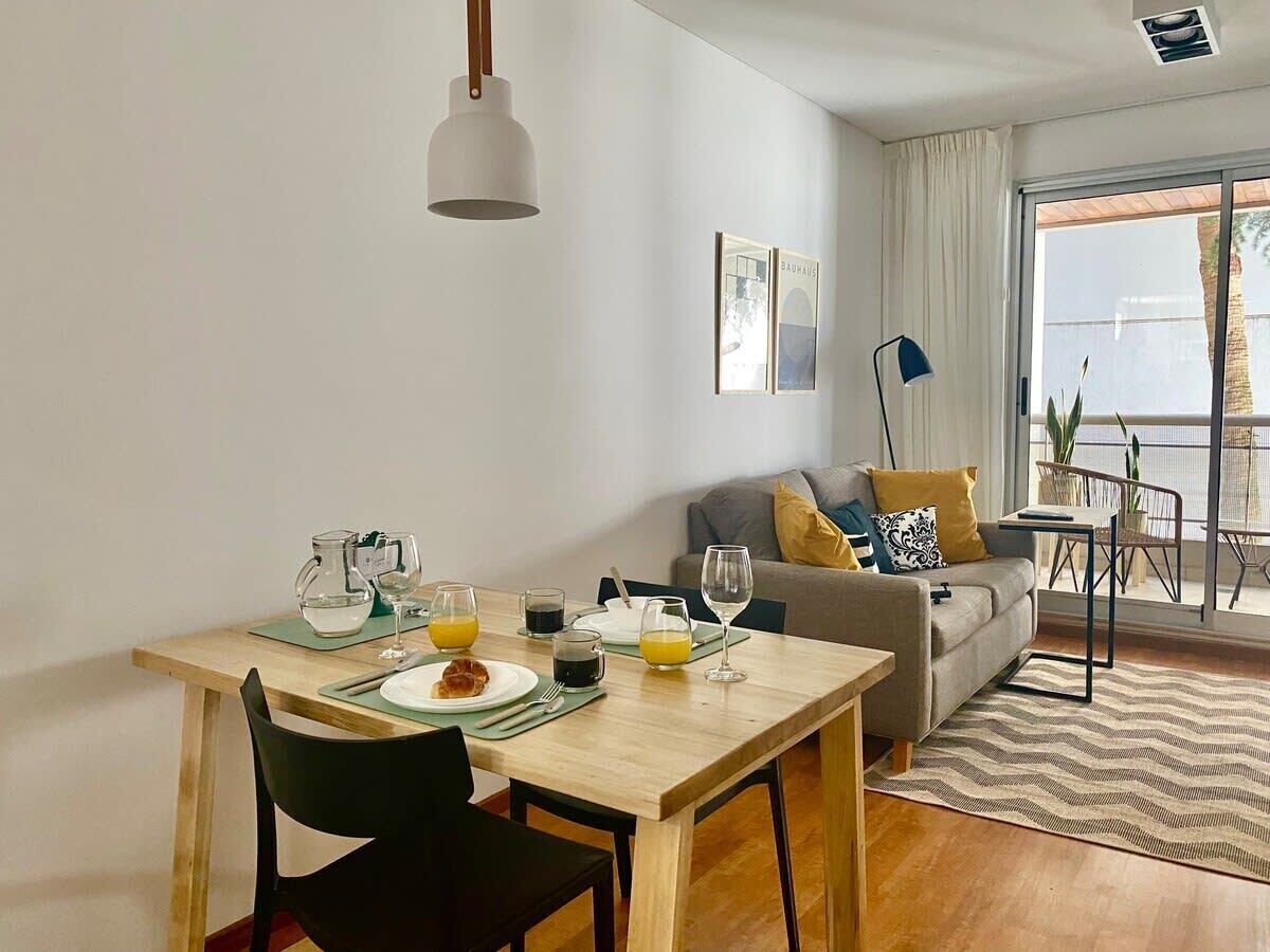 Un coin repas avec une table mise pour le petit-déjeuner, un canapé et un balcon avec vue.