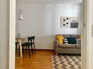Un salon avec un canapé, une table à manger et des chaises, ainsi qu’un tapis à motifs.
