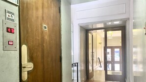 A hallway with a wooden door, a metal fire alarm panel, and a glass door leading to a room. - 157- Apt. with Great Location for 3 p. in Recoleta (Buenos Aires)
