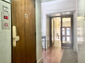 A hallway with a wooden door, a metal fire alarm panel, and a glass door leading to a room. - 157- Apt. with Great Location for 3 p. in Recoleta (Buenos Aires)