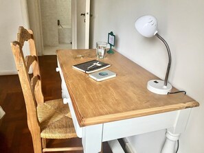 Ein Holztisch mit einer weißen Schreibtischlampe, einem Glas Wasser und einem Notizbuch.