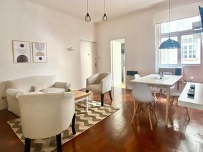 Ein Wohnzimmer mit Sofa, Sessel, Esstisch und Stühlen.