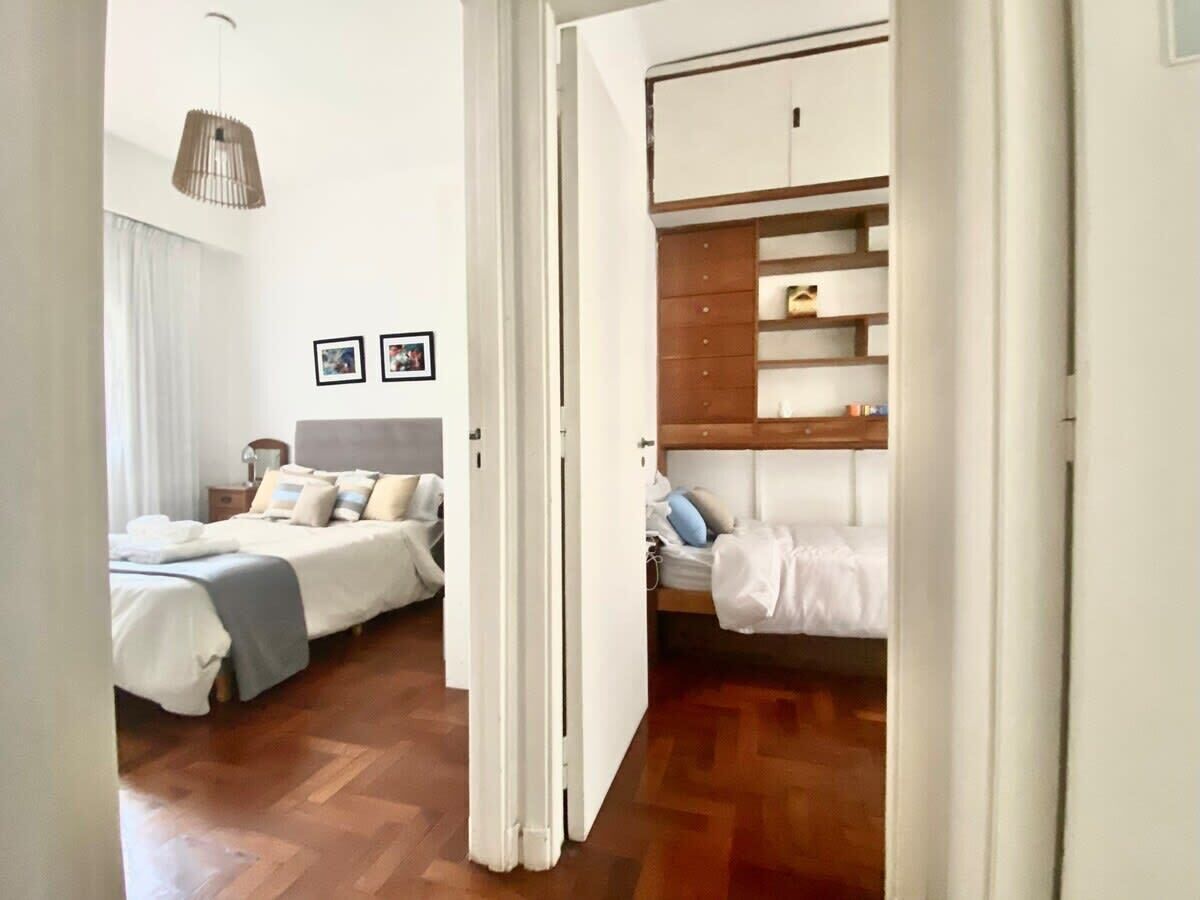A hotel room with two beds, a wardrobe, and a hanging light fixture.
