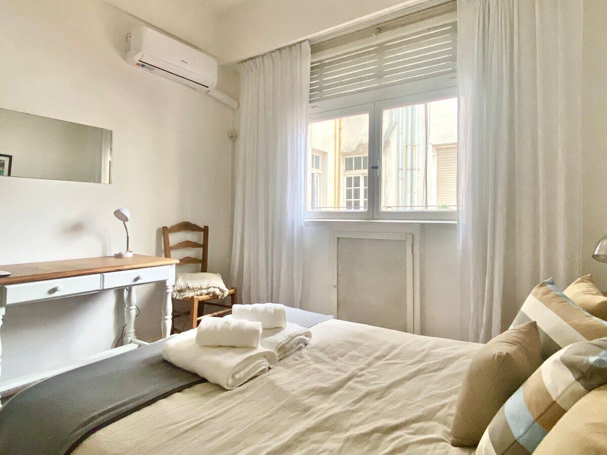 A hotel room with a bed, a desk, a chair, and a window with curtains.