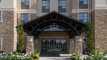 A hotel entrance with a stone facade, large windows, and a central archway.