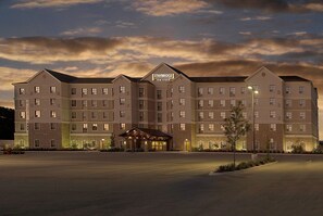 A multi-story hotel with a central entrance and a parking lot in front.