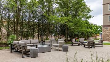 Un espace extérieur aménagé en terrasse, avec des sièges, un foyer et un mur en pierre.