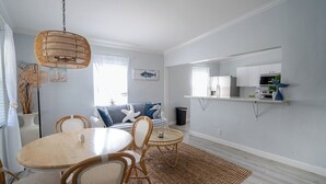 A modern living room with a dining area, featuring a round table, wicker chairs, and a hanging light fixture. - Renovated Coastal Hideaway • 2BR • Minutes to Beach • Private Parking & 65” TV (Boynton Beach)