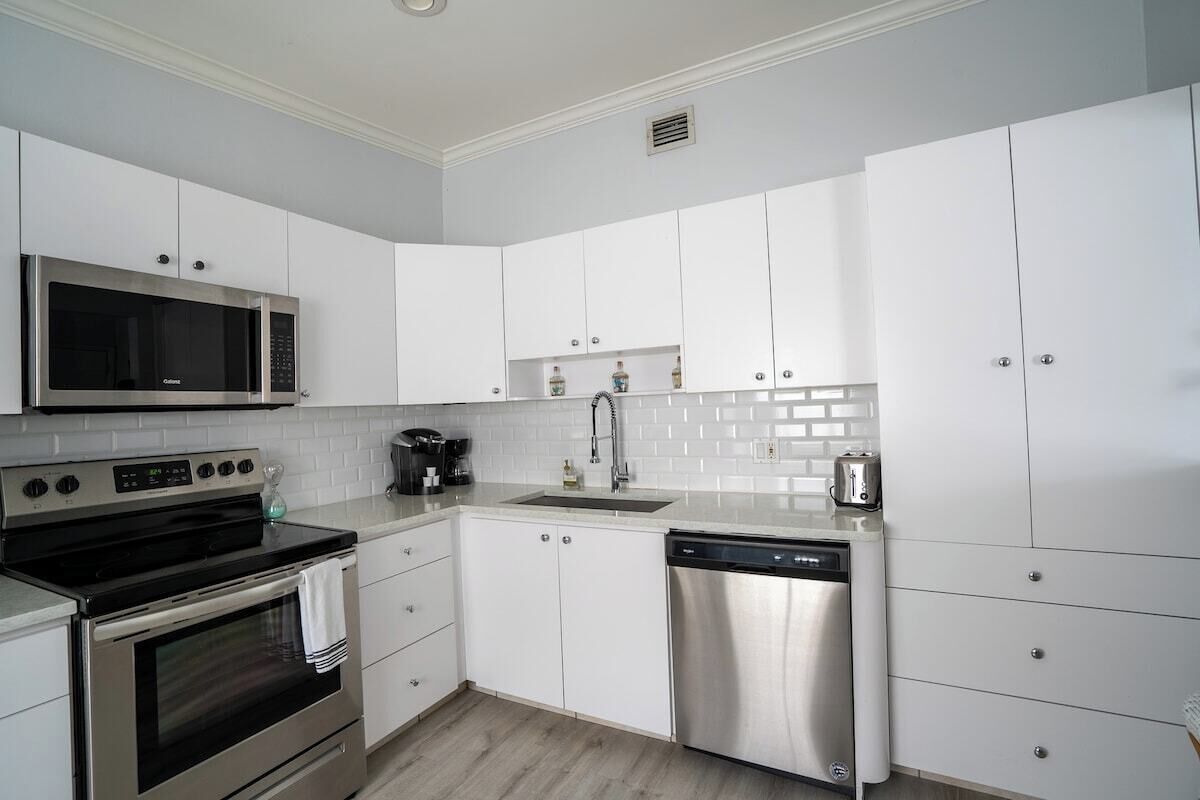 A modern kitchen with white cabinets, stainless steel appliances, and a tiled backsplash.