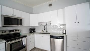 A modern kitchen with white cabinets, stainless steel appliances, and a tiled backsplash.