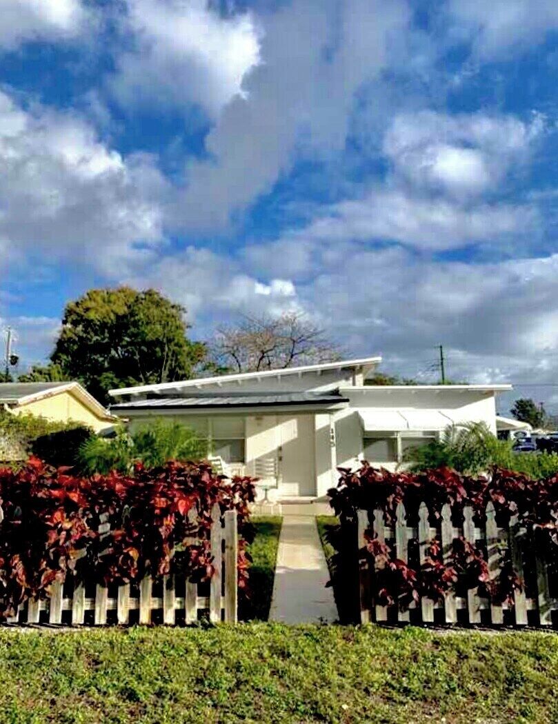 Une maison moderne à l’extérieur blanc, dotée d’un porche et d’une allée menant à l’entrée.