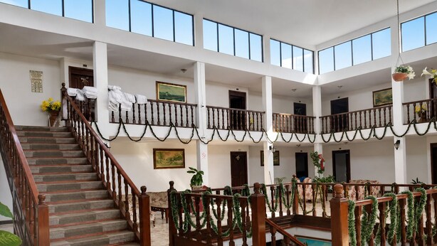 Un amplio atrio con una escalera central, varios balcones y un techo alto.