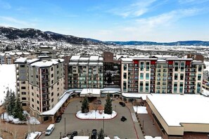 A hotel complex with multiple buildings, a parking area, and a view of snow-covered mountains. - Ski-in/out 2-bedroom suite at world-class Sheraton Steamboat Springs (Steamboat Springs)