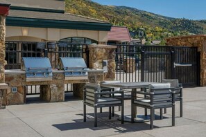 Une terrasse extérieure avec des barbecues en pierre, une table et des chaises.